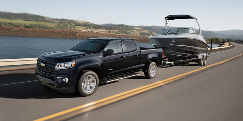 2022 Chevrolet Colorado towing a boat on a highway.