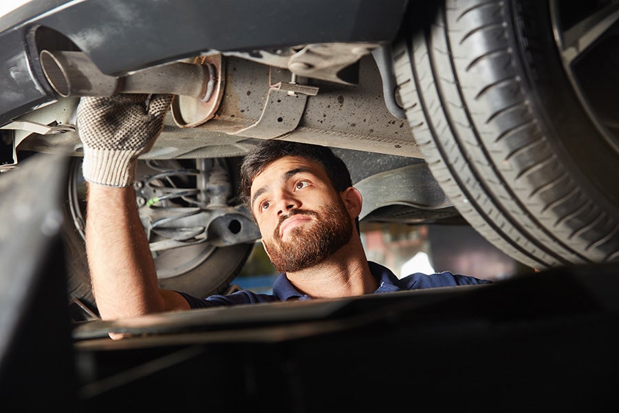 Chevy service technician working on a car exhaust system